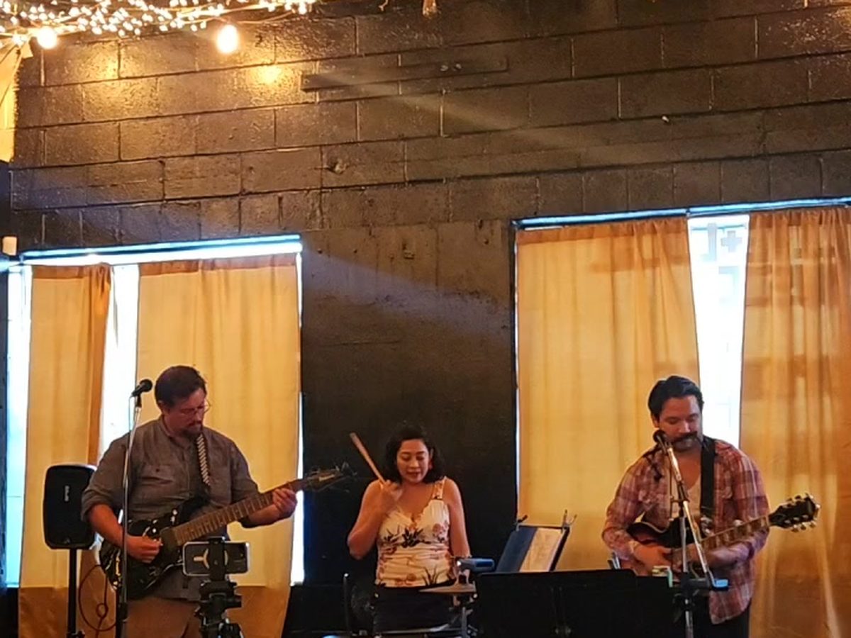 A band playing beneath string lights at Midtown Meetup