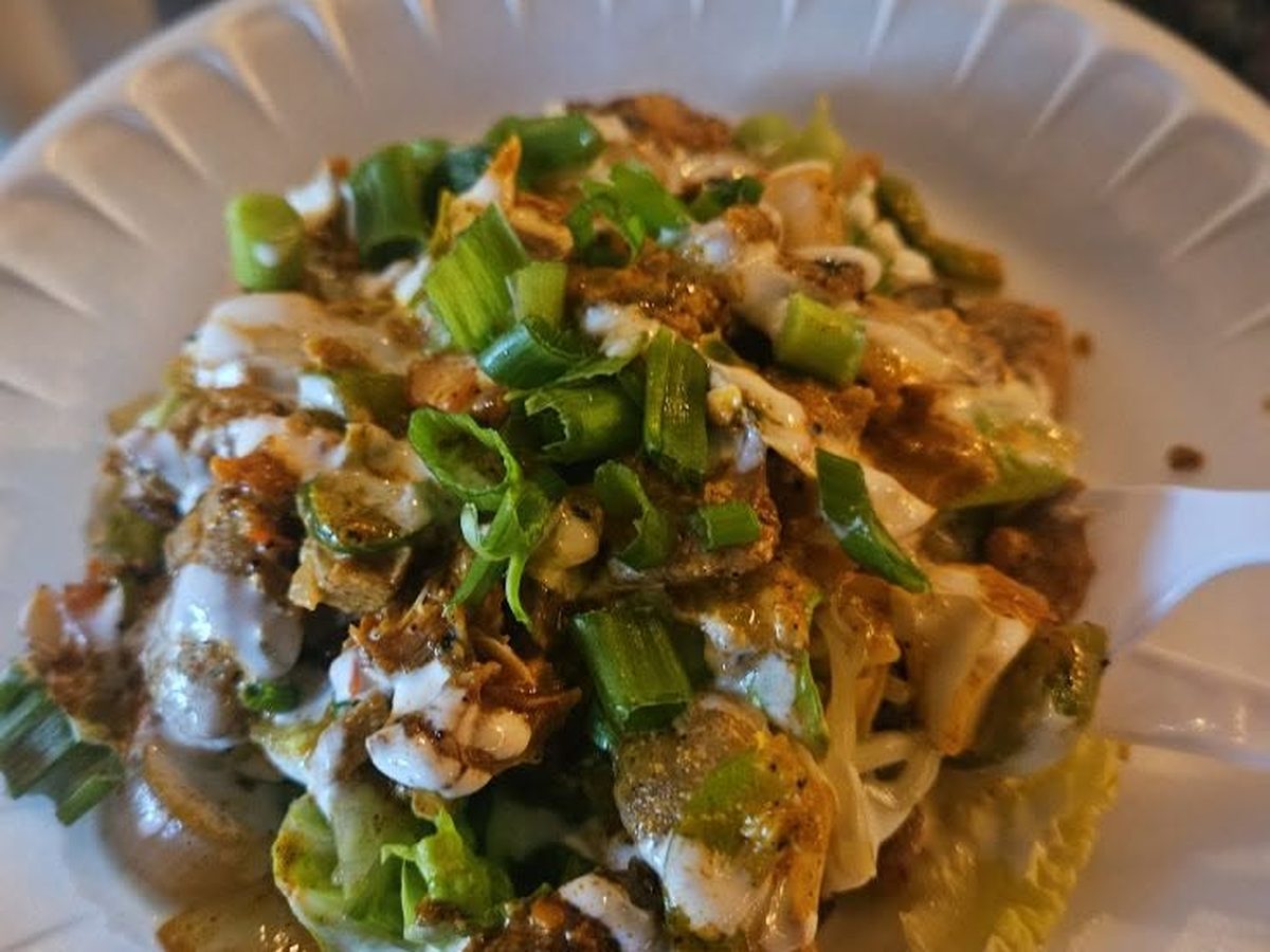 A loaded potato heaped with toppings and green onions