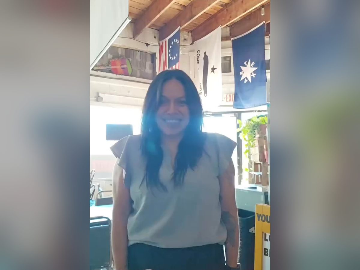 Mia standing in the shop beneath the Texas flags