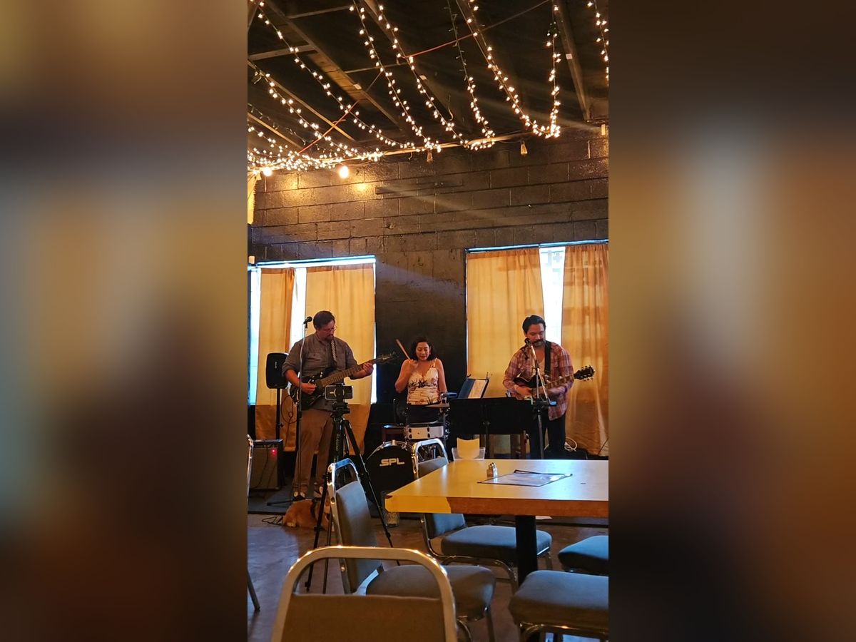 A band playing beneath string lights at Midtown