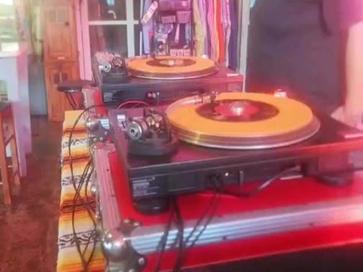 A DJ cutting records on turntables under pink light at Midtown