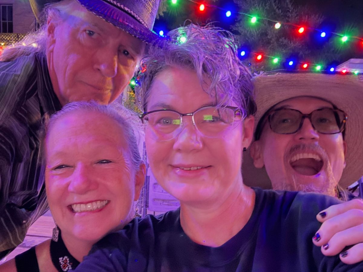 Friends crowding into a selfie under colored string lights